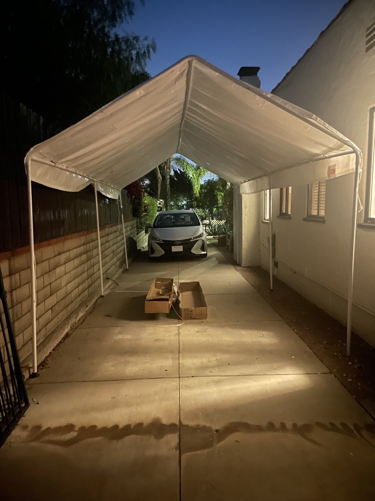 A simple carport—tarp over a tent structure made of metal tubing—assembled in a driveway